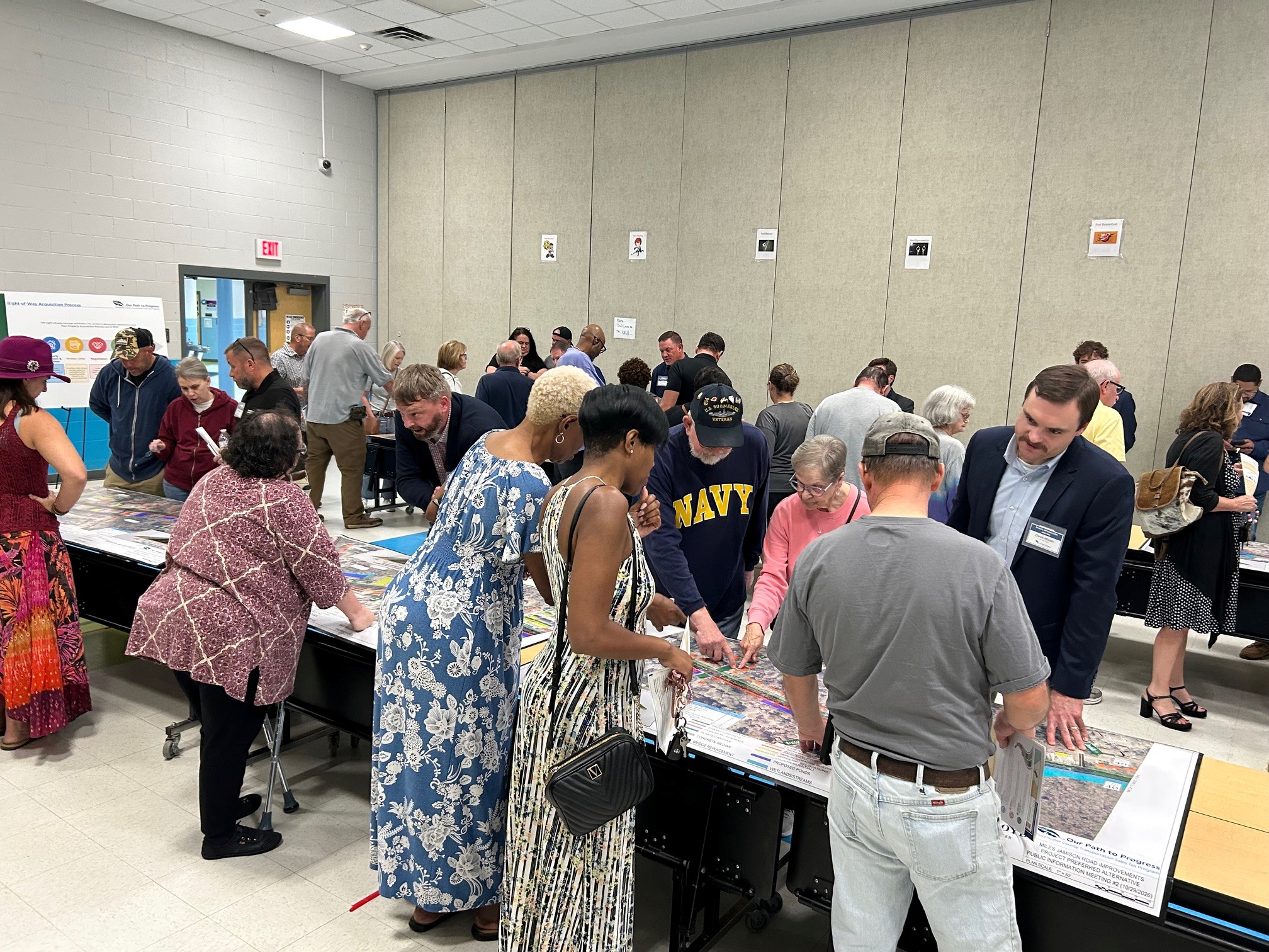 Community members gathered around tables reviewing public meeting materials. 